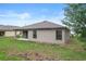 Back exterior of the home with covered patio, sliding glass door, neutral toned walls, lawn, and surrounding trees at 269 Fig Ct, Kissimmee, FL 34759