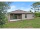 Back exterior of the home with a covered patio, sliding glass door, manicured lawn, and a large tree at 269 Fig Ct, Kissimmee, FL 34759