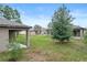 A spacious backyard, featuring a large tree, well-kept lawn, neutral toned siding, and a covered patio at 269 Fig Ct, Kissimmee, FL 34759