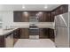 Modern kitchen featuring stainless steel appliances, dark cabinets, granite countertops and tile flooring at 269 Fig Ct, Kissimmee, FL 34759
