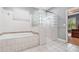 Bathroom with a glass block shower, a separate tub, and white tile throughout at 433 Tangerine Ave, Lake Helen, FL 32744