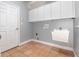 Functional laundry room with storage cabinets, utility sink, and tile flooring at 433 Tangerine Ave, Lake Helen, FL 32744