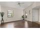 Bright living room with dark, wood-look floors, two windows, a ceiling fan, and a modern, minimalist aesthetic at 4643 Fern Pine Dr, Orlando, FL 32808