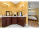 Bathroom with wood vanity, quartz counters, mirrors and access to the main bedroom at 507 Westwind Dr, Davenport, FL 33896