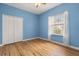 Empty bedroom with blue walls, white closet doors, wood-look floors, and window at 507 Westwind Dr, Davenport, FL 33896