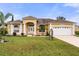 Inviting single-story home with a well-manicured lawn, columns, and a two-car garage at 507 Westwind Dr, Davenport, FL 33896