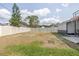 Partially grassy backyard has a white fence, with trees beyond, and a patio with basketball hoop at 528 Courtland Blvd, Deltona, FL 32738