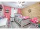 Vibrant pink bedroom complemented by a wooden accent wall, equipped with a ceiling fan, and filled with colorful decor at 528 Courtland Blvd, Deltona, FL 32738