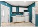 Compact kitchen with white cabinets, appliances, and contrasting teal walls and tile flooring at 5338 Tangerine Ave, Winter Park, FL 32792