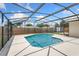 A view of the pool with a screened enclosure, stone surround, and fence in the background at 5338 Tangerine Ave, Winter Park, FL 32792