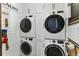 Bright laundry room features a stacked washer and dryer, white cabinets, and shiplap walls at 557 Lake Cove Pointe Cir, Winter Garden, FL 34787