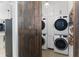 Convenient laundry room with modern stacked appliances, storage cabinets, and a sliding barn door at 557 Lake Cove Pointe Cir, Winter Garden, FL 34787