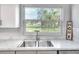 Bright and functional kitchen with stainless steel sink, views through a picture window, and stone countertops at 642 Carver Dr, Lake Wales, FL 33853