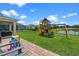 Well-manicured backyard featuring a playground with swings and a slide, near a serene pond at 646 Marsh Reed Dr, Winter Garden, FL 34787