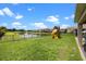 Spacious backyard with green grass, a playground set, and a serene pond view at 646 Marsh Reed Dr, Winter Garden, FL 34787