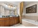 Bathroom featuring double sinks, a bathtub, and warm, neutral tones for a relaxing atmosphere at 7660 Whisper Way # 402, Reunion, FL 34747