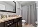 Well-lit bathroom with a granite countertop vanity, dark cabinetry, and shower with neutral-toned shower curtain at 8122 Roseville Rd, Davenport, FL 33896