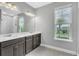 Primary bath featuring dual sinks, modern lights, and a large window at 8226 Nemours Pkwy, Orlando, FL 32827
