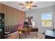 Well-lit home office featuring unique wooden accent wall, ceiling fan, and large window at 1123 Dora Parc Ln, Mount Dora, FL 32757