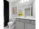 Well-lit bathroom featuring a gray vanity, quartz countertop, decorative mirror, and black accents from the shower curtain at 11360 Blue Bay Dr, Orlando, FL 32832