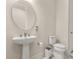 Elegant powder room with a pedestal sink, round mirror, and modern fixtures at 13462 Panama Beach Ct, Orlando, FL 32827