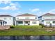 Back exterior of a two-story home with a lawn leading down to a pond in a residential neighborhood at 13758 Tybee Beach Ln, Orlando, FL 32827