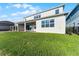The backyard features a lush green lawn extending from the white home with large windows and a covered patio at 13758 Tybee Beach Ln, Orlando, FL 32827