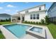 Backyard featuring a modern pool, spa and landscaping against the white exterior of the house at 13758 Tybee Beach Ln, Orlando, FL 32827