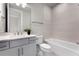 Bright bathroom with a vanity, toilet, and bathtub featuring tiled walls and floors at 13758 Tybee Beach Ln, Orlando, FL 32827