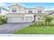 Charming two-story home featuring a three-car garage, brick driveway, and a well-manicured lawn at 13758 Tybee Beach Ln, Orlando, FL 32827
