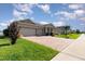 View of a single-story home featuring a brick driveway, lush green lawn, and a two-car garage at 2249 Palmetum Loop, Apopka, FL 32712