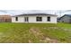 The backyard features a well-maintained lawn and a white house with black trim windows and a back door at 2486 Ainsworth Ave, Deltona, FL 32738
