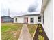 The exterior showcases a white house with black trim windows and a red front door at 2486 Ainsworth Ave, Deltona, FL 32738