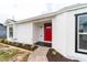 Inviting front entry featuring a red door, crisp white siding, and newly landscaped garden beds at 2486 Ainsworth Ave, Deltona, FL 32738
