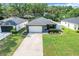 Aerial view of a modern one-story home, featuring green lawn and concrete driveway at 25106 Quaker Ridge Ave, Sorrento, FL 32776