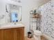 Bathroom with wood vanity, shelving unit, toilet, and bathtub/shower with blue butterfly shower curtain at 2662 Mayaguana St, Kissimmee, FL 34747