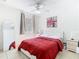 Bright bedroom with white ceiling fan, white furniture, red bedspread, mirror, and tile floors at 2662 Mayaguana St, Kissimmee, FL 34747