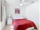 Bright bedroom with white ceiling fan, white furniture, red bedspread, and tile floors at 2662 Mayaguana St, Kissimmee, FL 34747
