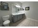 Neat bathroom featuring gray cabinetry, framed mirror, and white tiled floor at 2785 Almaton Loop # 204, Kissimmee, FL 34747