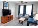 Bright living room features a blue sofa, patterned armchairs, a wooden coffee table, and neutral walls and tile flooring at 2785 Almaton Loop # 204, Kissimmee, FL 34747