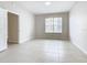 A cozy bedroom with neutral paint, white door, tile flooring, and a window at 3000 Laurel Park Ln # 202, Kissimmee, FL 34741