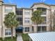 Condo building with awning over the entry, mature palm trees, covered parking and lovely manicured landscaping at 3000 Laurel Park Ln # 202, Kissimmee, FL 34741