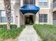 Charming building entrance with a blue awning, well-maintained landscaping, and visible unit numbers at 3000 Laurel Park Ln # 202, Kissimmee, FL 34741