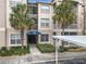 Attractive building featuring a covered entrance, palm trees, well-maintained landscaping, and a nearby parking spot at 3000 Laurel Park Ln # 202, Kissimmee, FL 34741