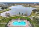Aerial view showcasing a community pool, lake with fountains, and surrounding residential buildings in a scenic setting at 3000 Laurel Park Ln # 202, Kissimmee, FL 34741