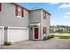 Gray two-story home featuring a white garage door, red door and shutters, and a brick driveway at 3039 Meleto Blvd, New Smyrna Beach, FL 32168