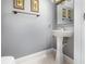 Half bathroom with a modern pedestal sink, mirror, and soft gray walls at 3063 Mandolin Dr, Kissimmee, FL 34744