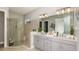 Well-lit bathroom with a double vanity, a glass-enclosed shower, and modern fixtures at 4215 Barbuda Ln, Kissimmee, FL 34758