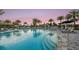 Community resort-style pool surrounded by lounge chairs, umbrellas, and palm trees at 4215 Barbuda Ln, Kissimmee, FL 34758