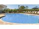 Sparkling blue pool with sun loungers, umbrellas, and tables for outdoor enjoyment at 491 Wayland Dr, Haines City, FL 33844
